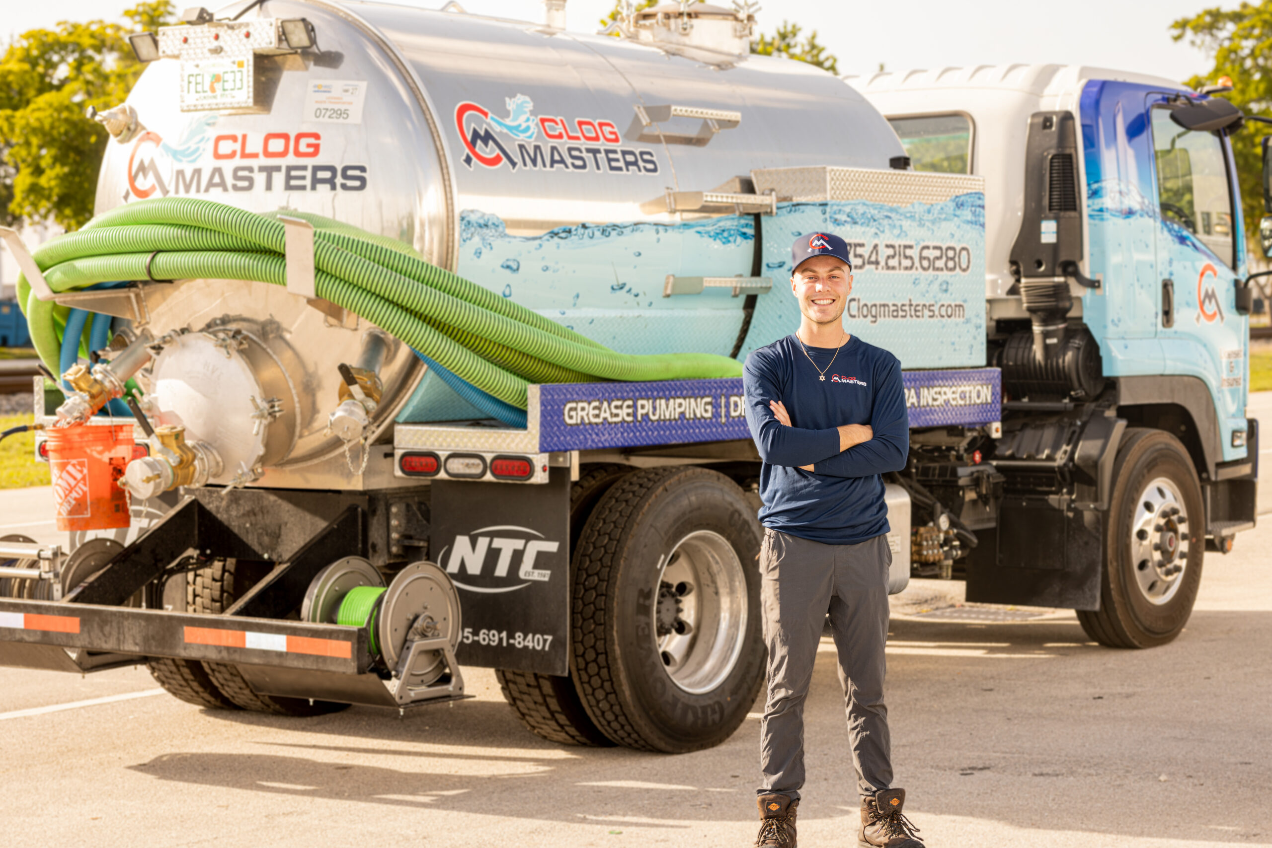 ClogMasters technician standing in front of a ClogMasters grease pumping truck in Hollywood, FL